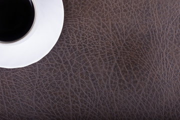 cup of coffee on a leather textured surface