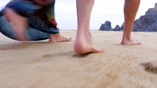 Close up of the feet of an older couple walking down the beach
