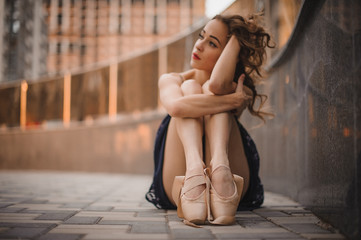  young beautiful modern style ballet dancer sitting on the ground in black dress . selective focus.