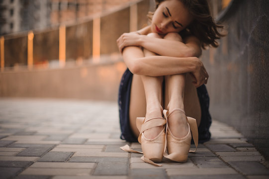  young beautiful modern style ballet dancer sitting on the ground in black dress . selective focus.