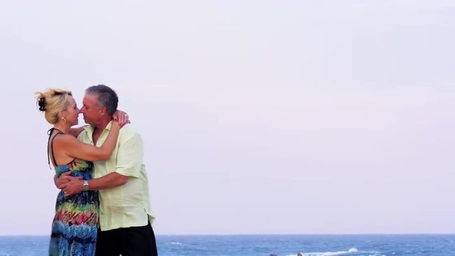 An older couple kiss on the beach