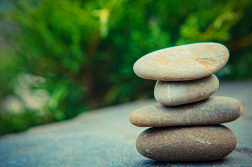 Stacked spa stones with a nature green background.