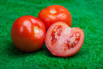 Close up of fresh tomatoes in drops of water on on the green grass