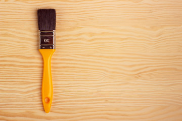 Yellow paint brush on a wooden background