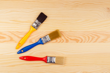 Set of colored brushes for repairs on a wooden background