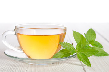 Glass cup of tea with mint on the white wooden table
