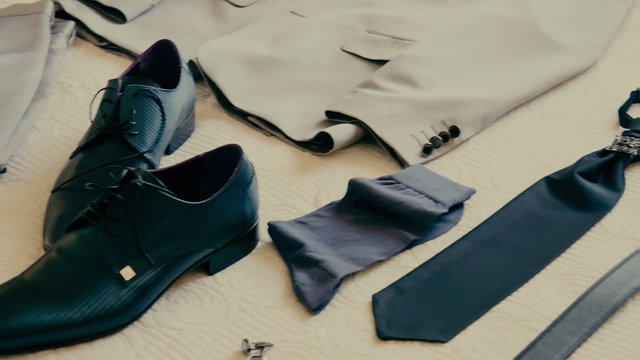 Groom's costume and wedding clothes layed,folded on a bed panning shot