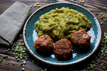 Meatballs served with green peas, selective focus, closeup