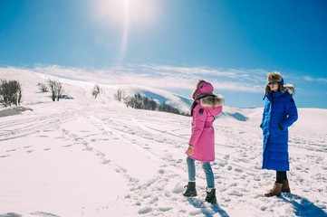 winter, two cheerful young girls having fun in the snow in the m