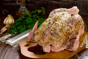 Raw chicken prepared for roasting and spices in a rustic style