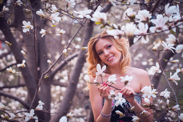 Beauty smiling woman near white magnolia