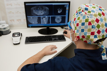 Concentrated male dentist looking at x-ray on computer