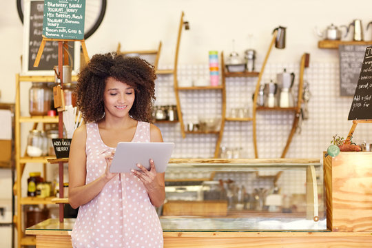 Small business owner using a digital tablet in her coffee shop