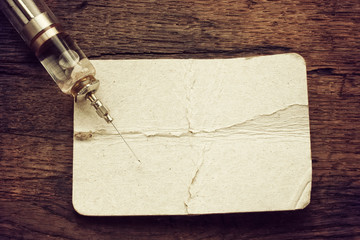 obsolete glass syringe on old wooden table