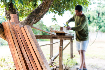 worker planing a plank of wood with a electric plane