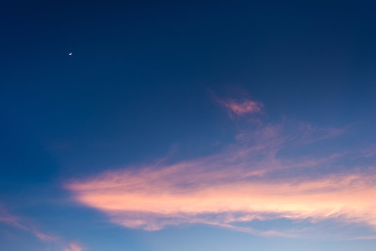 pink cloud and moon in blue sky