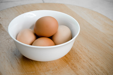 the five eggs in white ceramic bowl on wood table