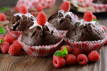 Delicious chocolate cupcakes with berries and fresh mint on wooden table close up
