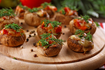A wooden tablet with stuffed mushrooms on the table, close-up