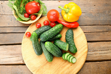 Composition of cucumbers, tomatoes and sweet peppers circles on wooden background