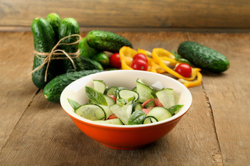 Vegetable salad with cucumbers on wooden background