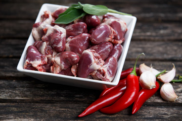 Raw Free range Duck hearts in squared plate, decorated with greens and vegetables. on old wooden table.