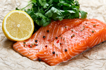 Raw Salmon fish fillet with fresh herbs on crumpled paper.