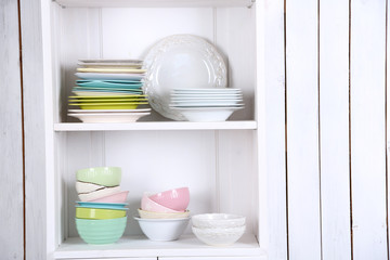 Different clean dishes on wooden shelves