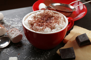 Cup of coffee and sweets on black wooden background