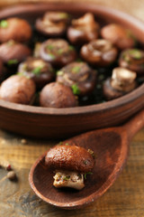 Baked champignons mushrooms with butter, parsley and roasted garlic in brown bowl