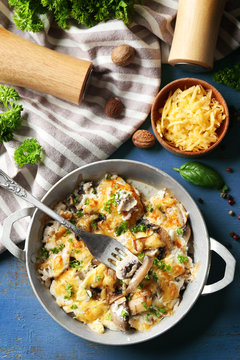 Roasted mushrooms, chicken and cheese gratin in pan, on color wooden background