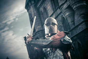 Medieval knight with the sword on the ancient castle background.