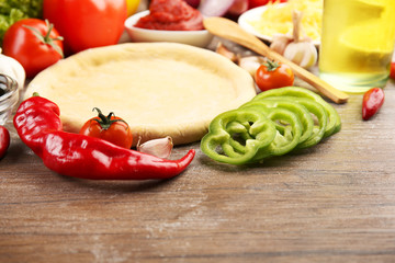 Dough basis and ingredients for pizza, on the table