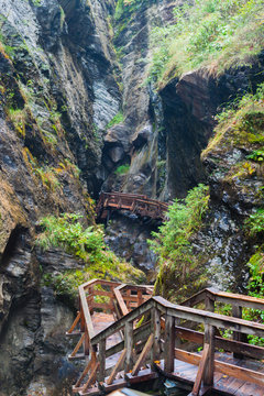 A wooden bridge along a vertical cliff over the precipice.
