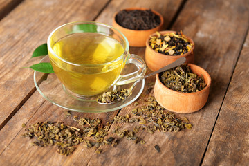 Glass cup of tea with mint leaves and herbs on wooden background