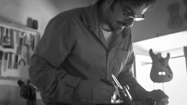 Handheld shot of Luthier making a violin