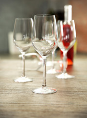 Empty wine glasses with bottle on wooden table against blurred background