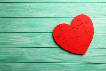 Red puzzle heart on mint wooden background