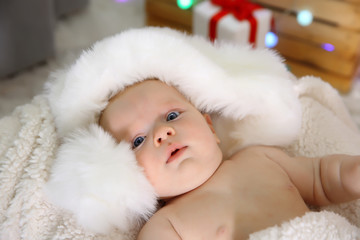 Obraz premium Cute naked baby in red hat on the warm blanket, close up