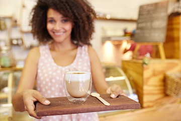 Latte on a wooden tray being carried by a young waitress