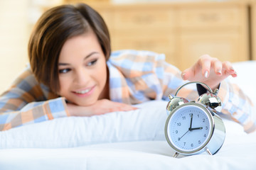 Young girl touching the alarm clock. 
