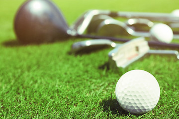 Different golf clubs  and balls on golf course, close up