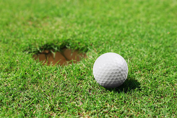 Golf ball on lip of cup on the green golf course