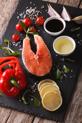 Raw salmon steak and ingredients close-up on a table. Vertical 
