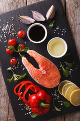 Raw salmon and ingredients on a slate board closeup. vertical top view