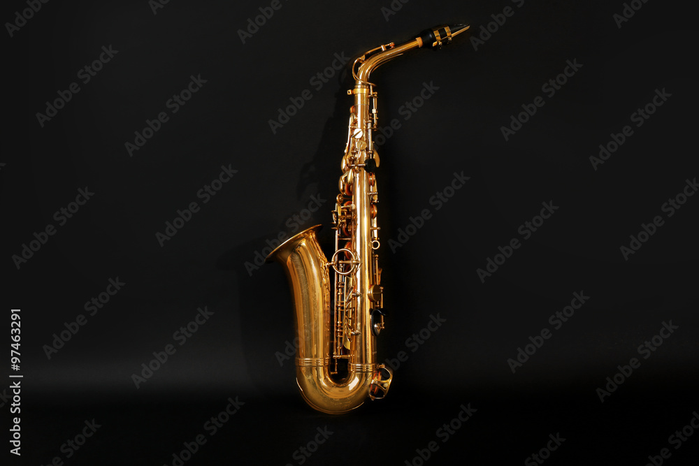 Wall mural Beautiful golden saxophone on black background