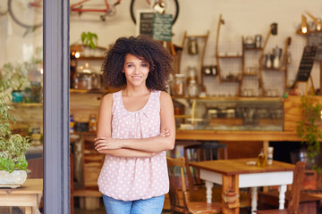 Small business owner standing proudly in the door of her coffee