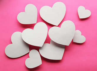 White paper hearts on pink background