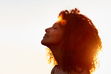 Profile of a woman with afro silhoutted against evening sun