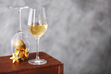 Glass of wine with Christmas toys on grey wall background